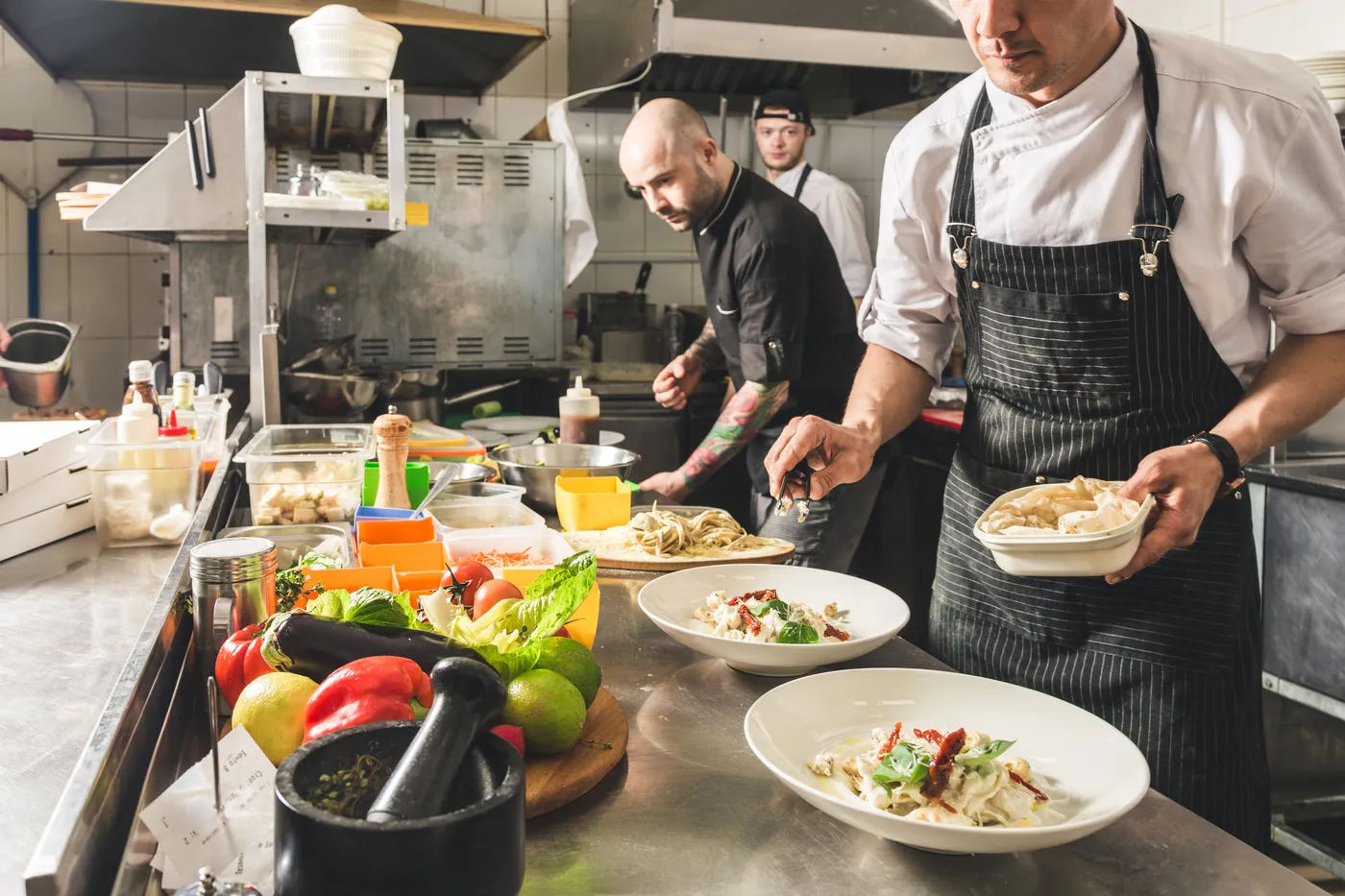 Reinhardt koch - Kochkurse und Gastronomie-Service - Ein professioneller Koch bereitet im Hotelrestaurant das Abendessen zu. Ein Koch in Schürze macht einen Gemüsesalat und Pizza.