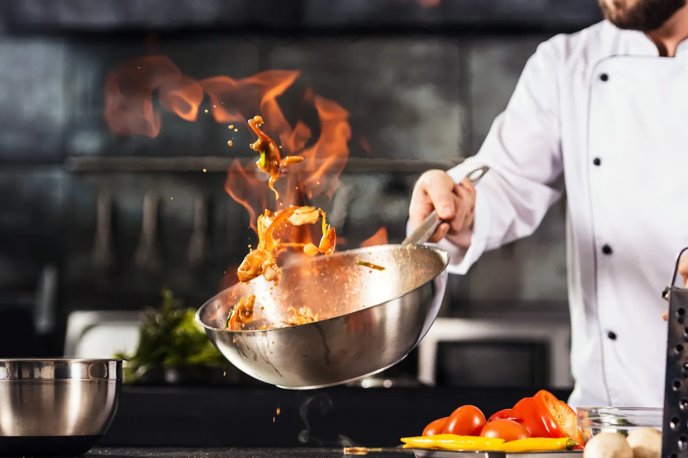 Reinhardt koch - Kochkurse und Gastronomie-Service - Die Hände eines Kochs halten den Wok über dem Feuer. Nahaufnahme: Die Hände eines Kochs bereiten Speisen über dem Feuer zu.